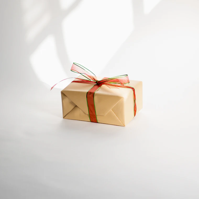 Un pacchetto regalo con nastro, su fondo chiaro