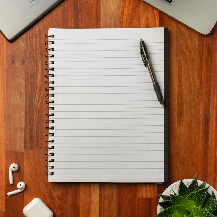 Un quaderno a righe con una penna, su un tavolo di legno