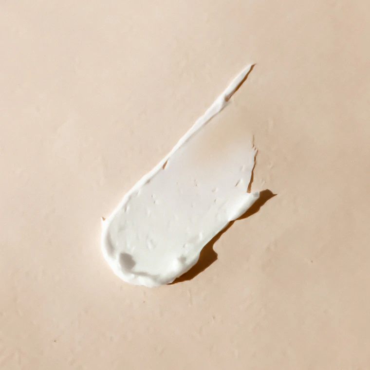Una crema dermocosmetica stesa su fondo chiaro