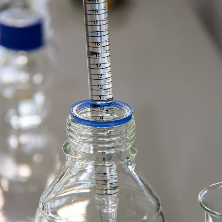 Una pipetta di laboratorio che dosa un liquido in un flacone di vetro